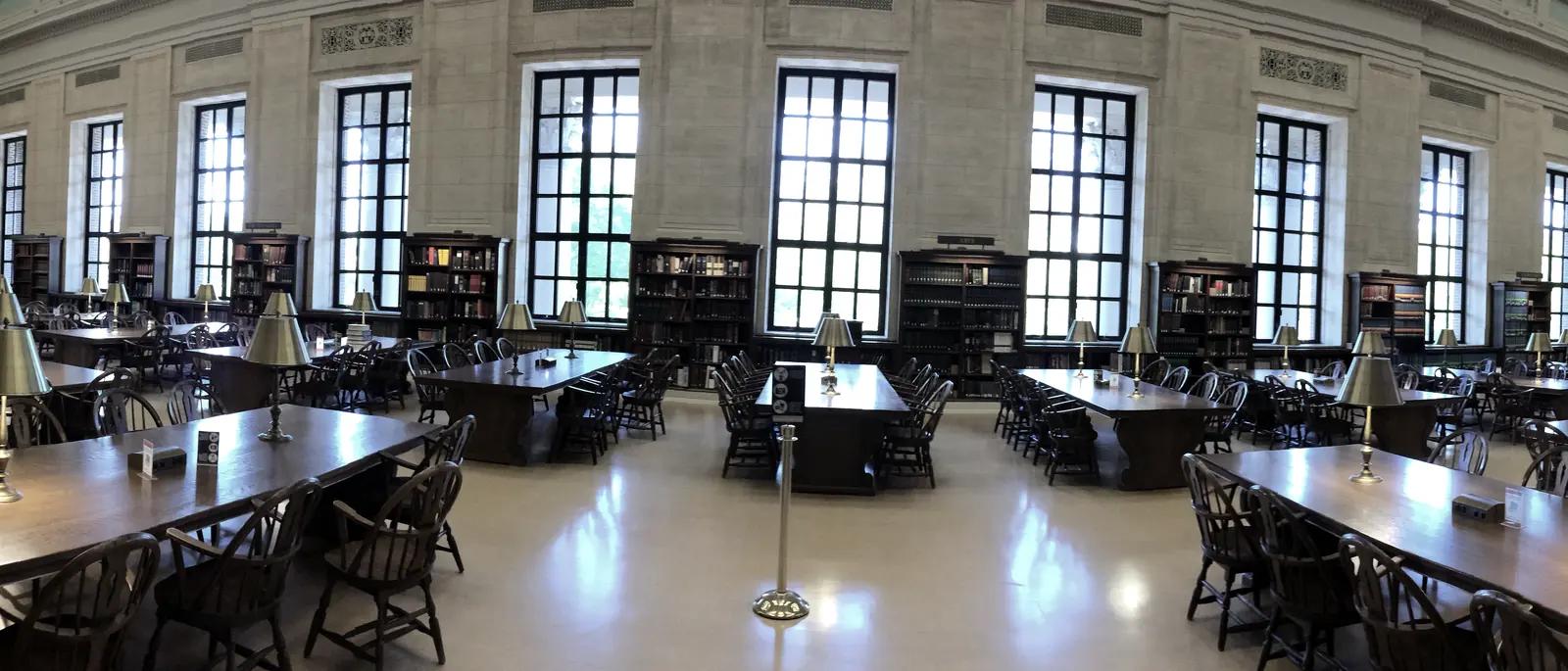 The Loker Reading Room in Widener Library at Harvard: long oak tables and green lamps beneath a vaulted ceiling.